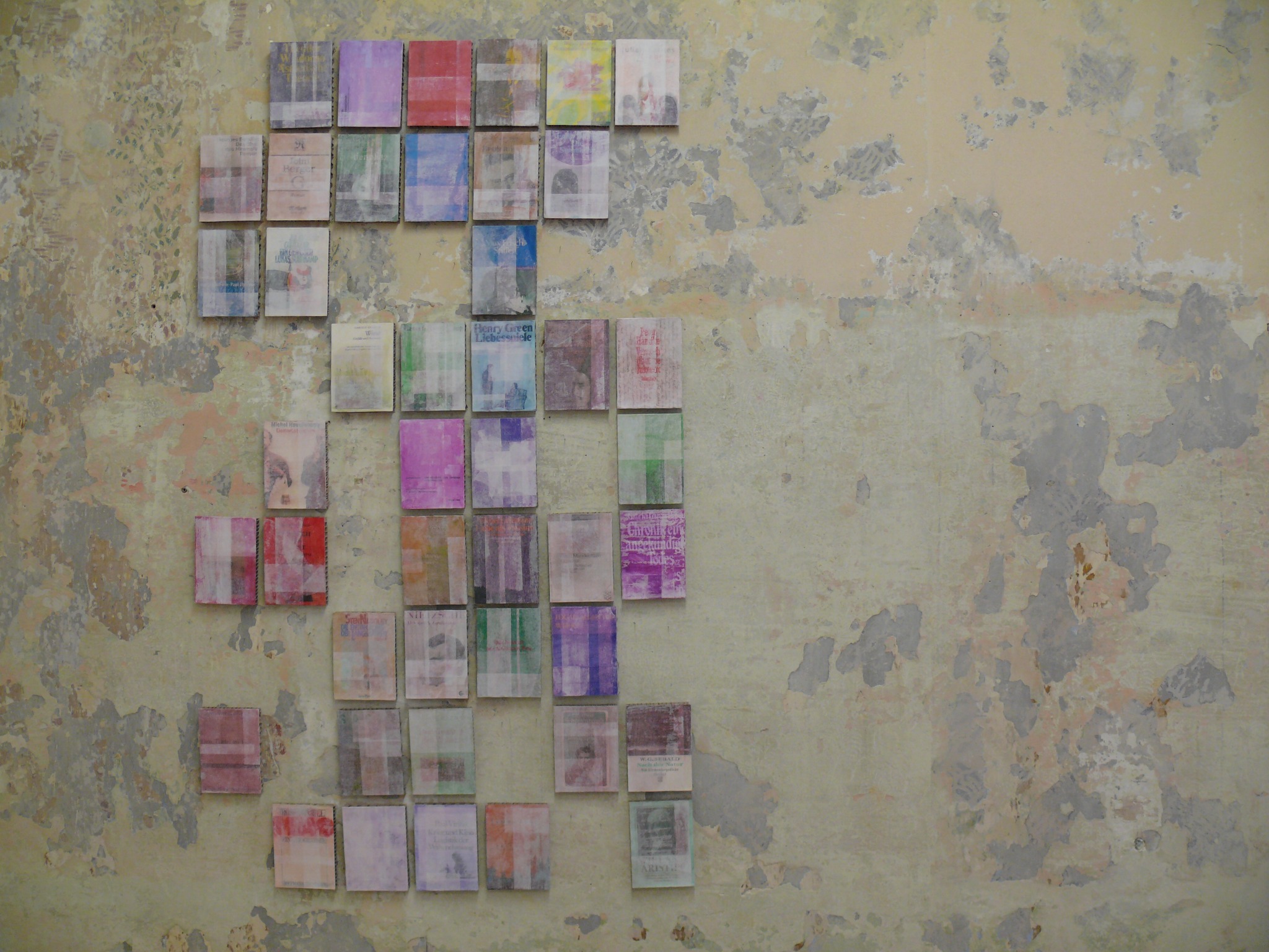 Frontal view of 63 cover paintings arranged on a wall